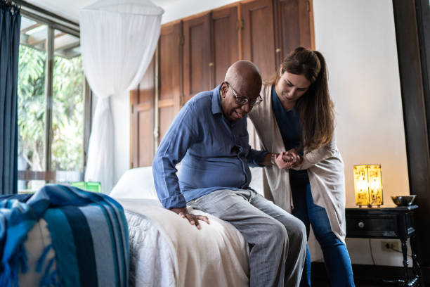 senior living employee helping a resident out of bed