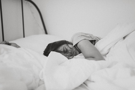 black and white photo of a woman sleeping in bed