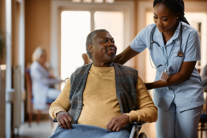 a nurse assisting a senior man in a wheelchair at a nursing home