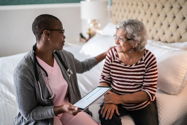 medical professional talking to a senior woman in the bedroom