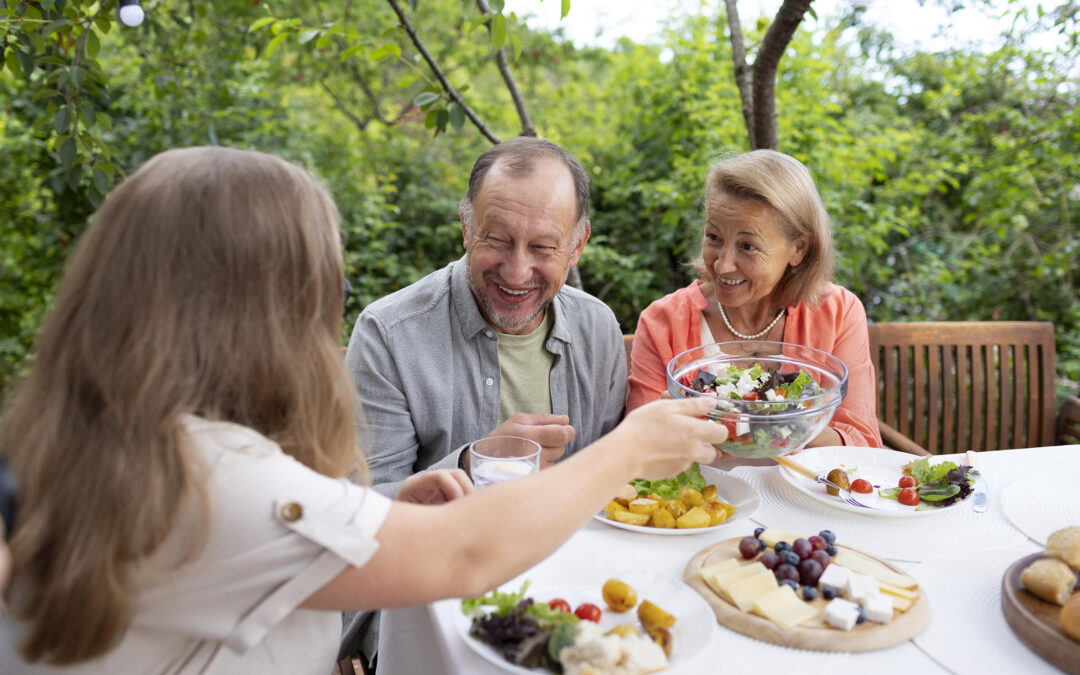 senior couple enjoy a meal outside with their daughter
